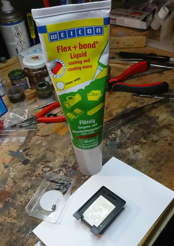 Тюбик клею Weicon Flex+bond стоїть на робочому столі поряд з моделлю візка, частково заповненою білою масою