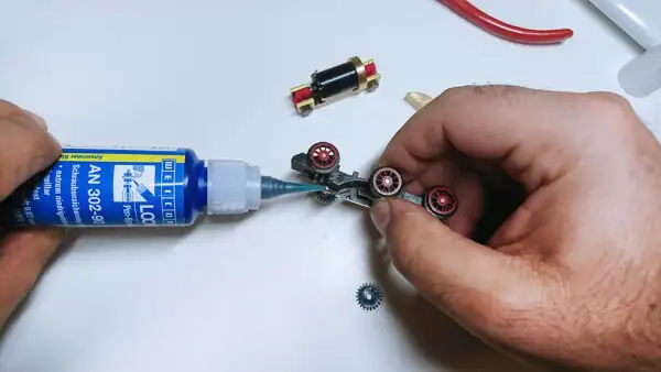 Людина наносить фіксуючий клей WEICONLOCK AN 302-90 на елементи шасі моделі з редуктором і колесами