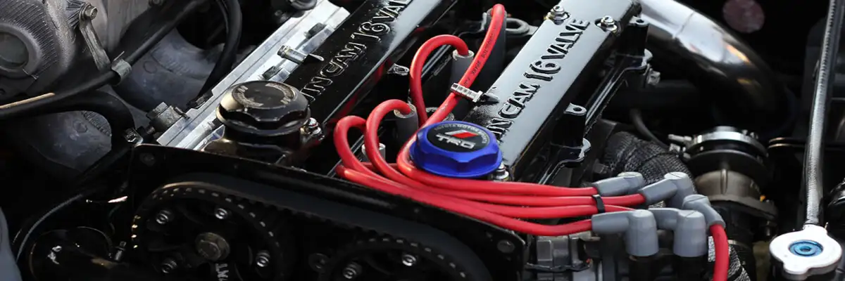 Автомобільний двигун з системою DOHC, червоними високовольтними дротами та 16-клапанною головкою.