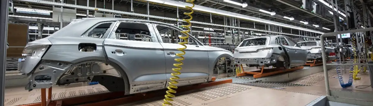 Виробнича лінія автомобілів на заводі, де каркаси кузовів проходять етапи складання та підготовки.