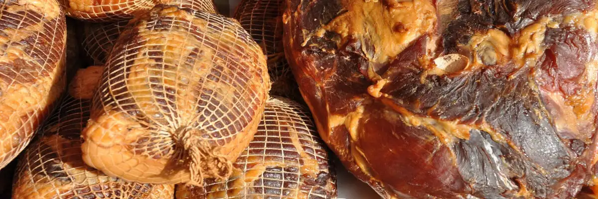 Копчёное и варёное мясо, упакованное в специальную сетку для формирования и хранения колбасных изделий.