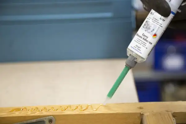Процес нанесення двокомпонентного епоксидного клею Weicon Epoxy Minute Adhesive зі шприца зі статичним змішувачем на дерев'яну деталь.