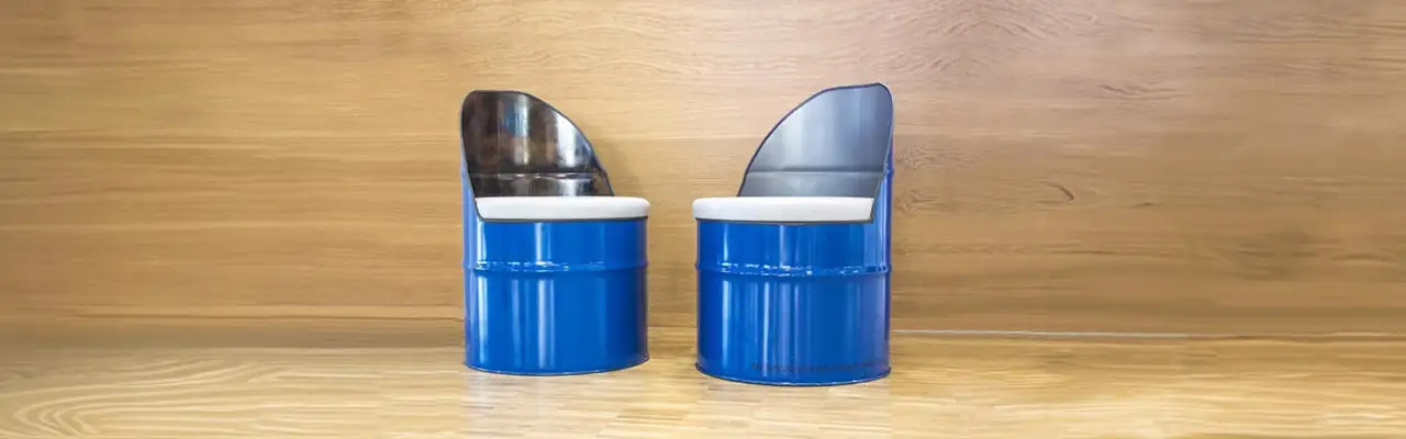 Два самодельных кресла/стула для мастерской, изготовленные в стиле DIY из разрезанных металлических бочек синего цвета с мягкими сиденьями.