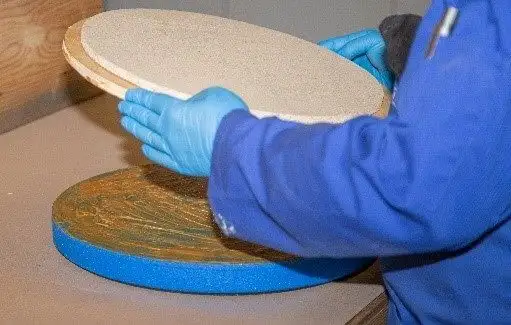 Соединение круглой деревянной плиты и синего поролона/губки, на которые нанесен контактный клей для резины и металла GMK 2410.