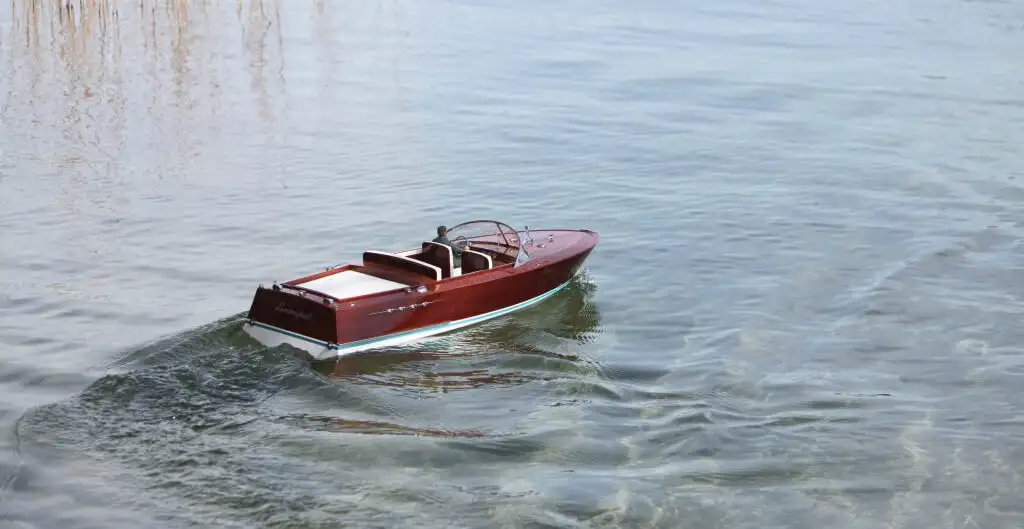 Модель моторной лодки Riva (Riva Aquarama) плывет по воде, демонстрируя результат использования эпоксидного клея Weicon для сборки и обеспечения водонепроницаемости корпуса.