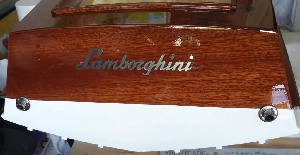 Встановлення хромованого логотипу 'Lamborghini' та інших декоративних елементів (як-от вентиляційні отвори) на дерев'яну модель човна, приклеєних технічним клеєм Weicon.