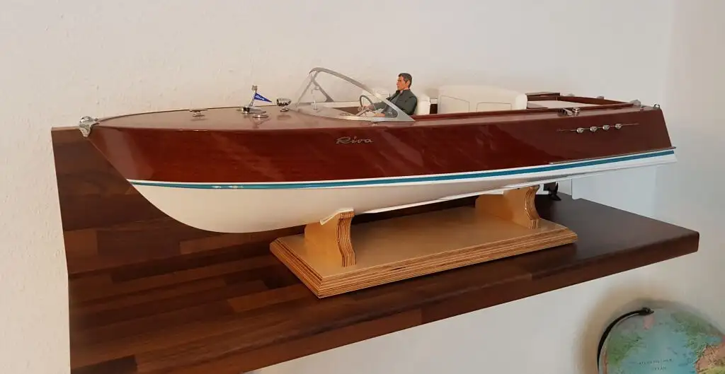 Готовая модель моторной лодки Riva (Riva Aquarama), собранная и декорированная, включая детали, приклеенные эпоксидным клеем Weicon. Модель стоит на деревянной подставке на полке.