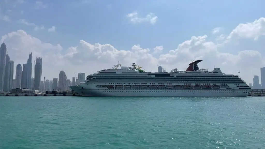 Великий круїзний лайнер Carnival Splendor пришвартований у порту на тлі сучасного міського пейзажу з висотними будівлями, що ілюструє морську та судноплавну галузь.