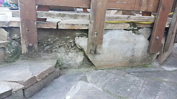Пошкоджений та крихкий пісковик під дерев'яною балюстрадою або перилами, що потребує ремонту та відновлення фасаду