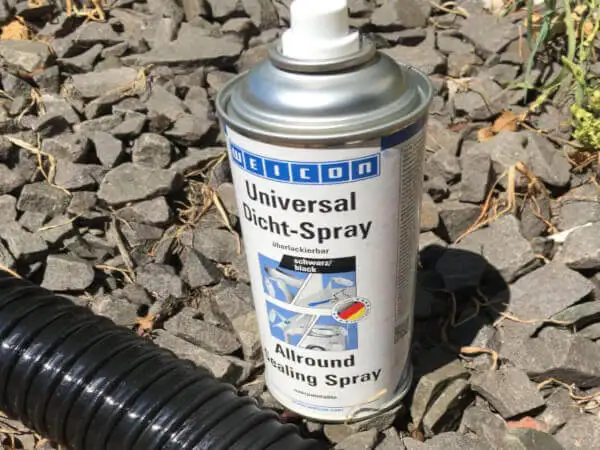 Чорний універсальний герметизуючий спрей WEICON Universal Dicht-Spray Allround Sealing Spray поруч із чорним гофрованим шлангом, готовий до герметизації