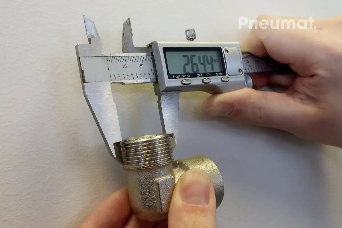 Вимірювання зовнішньої різьби кутового фітинга (коліна 90°) цифровим штангенциркулем. Результат виміру: 26.44 мм.