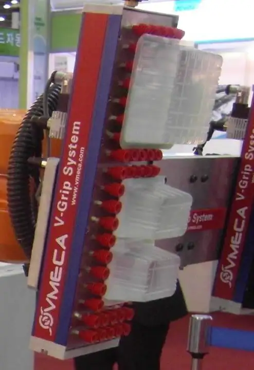 Вертикально розташований вакуумний модуль VMVMECA V-Grip System, демонструє принцип роботи, захоплюючи пластикові контейнери (пляшки) за допомогою численних червоних всмоктувальних насадок.