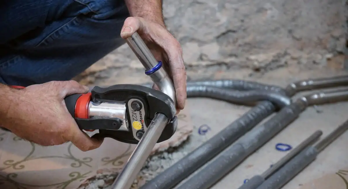 Процесс опрессовки стальных труб для монтажа системы охлаждения воды в помещении