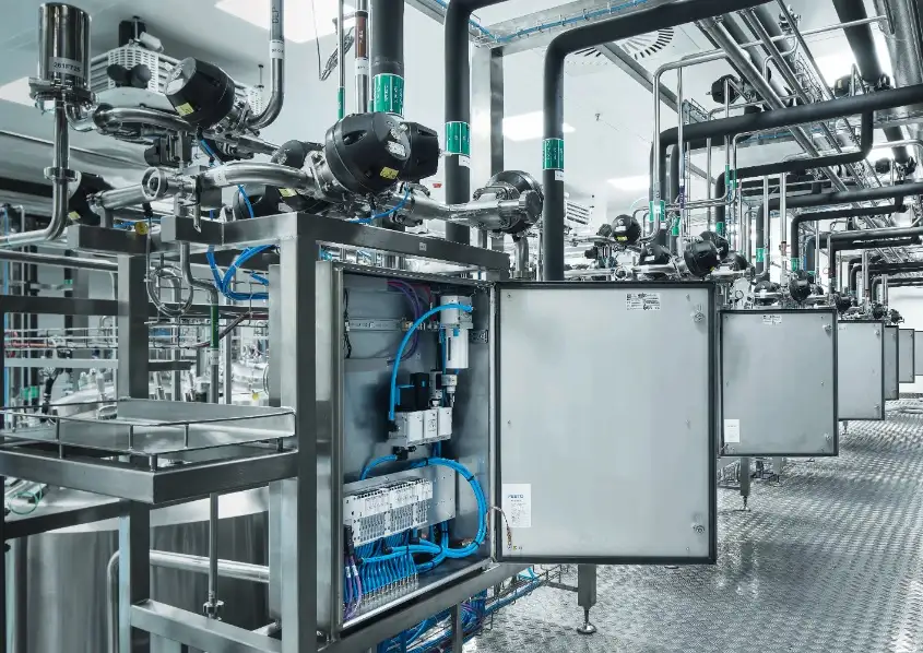 Промышленное оснащение FESTO: открытый шкаф управления с пневмоостровами и подключенной арматурой на производстве